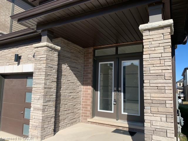 Stone veneer facade, covered entry, double entry doors, transom window, and integrated garage door