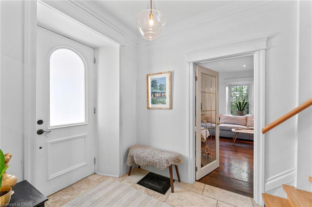 Arched entry door with frosted glass, crown molding, a glass pendant light fixture, and tile flooring