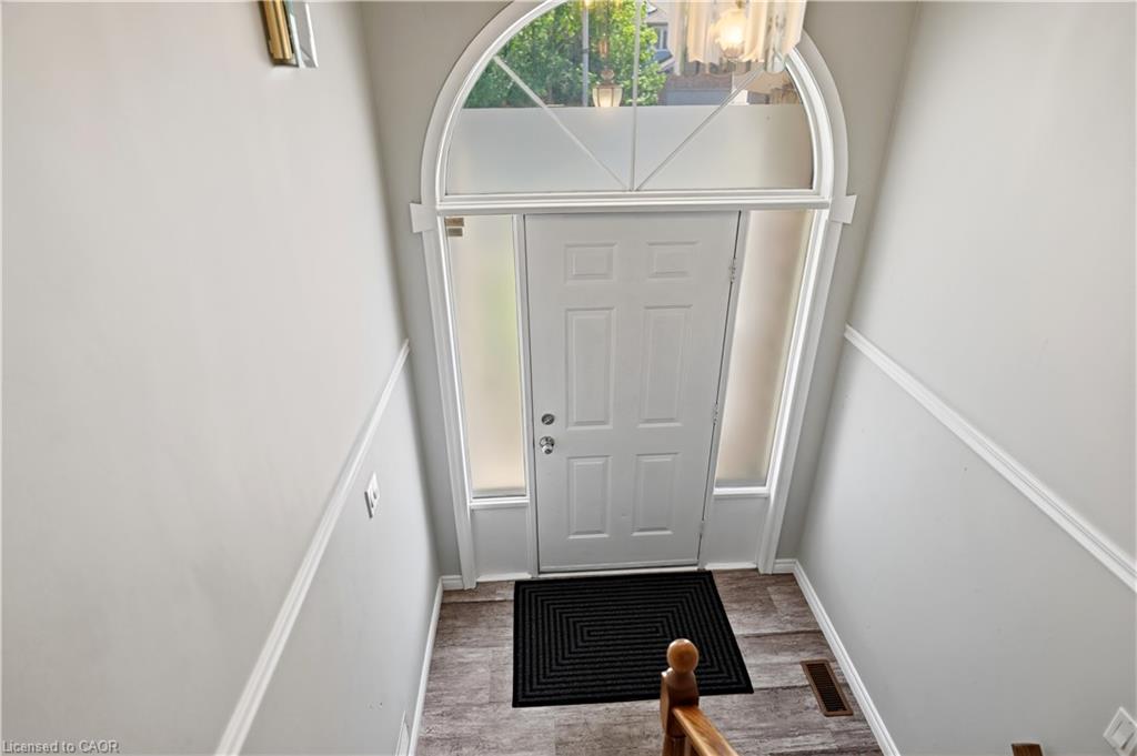 Entryway featuring an arched transom window, frosted sidelights, and wood-finish flooring