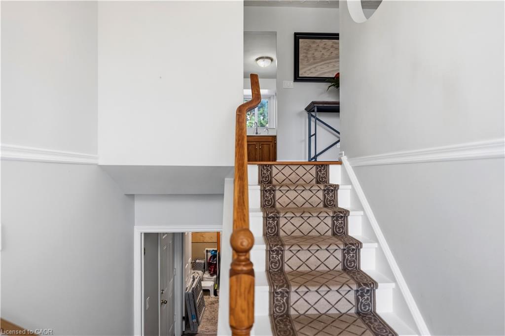 Staircase featuring a wood banister, patterned stair runner, and white risers