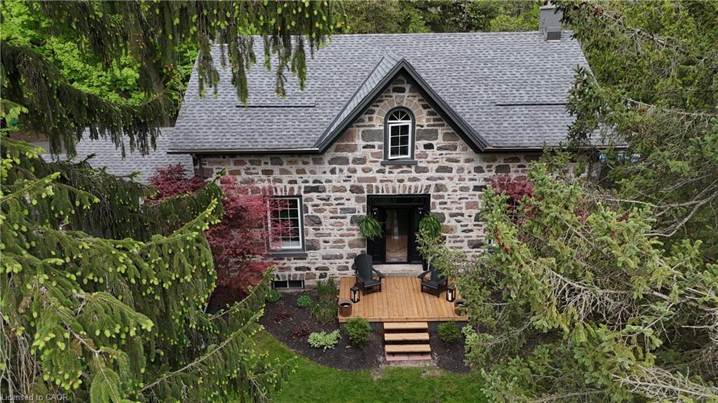 Stone exterior residence featuring a steeply pitched roof with asphalt shingles