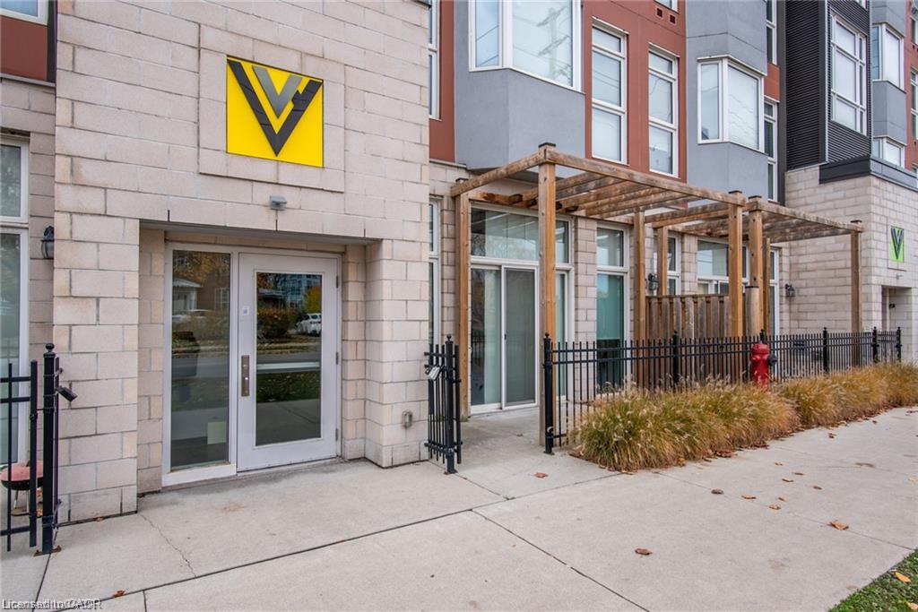 Stone-clad building exterior featuring a prominent entrance with glass doors, alongside a private patio area with a wooden pergola