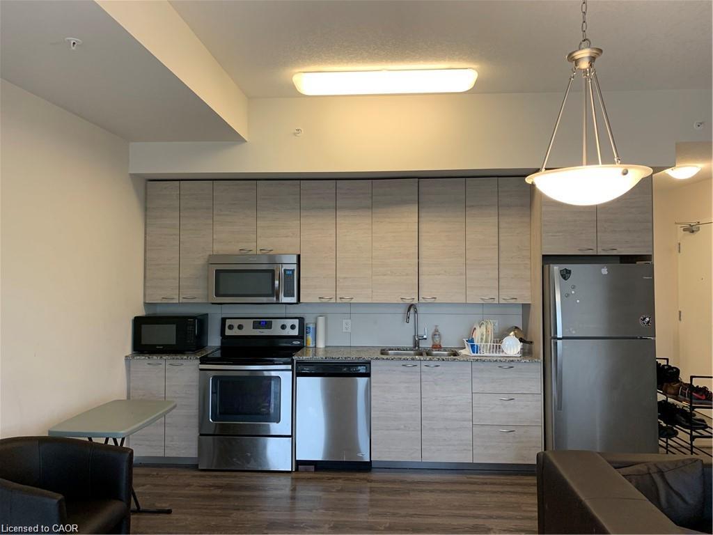 Kitchen featuring light wood-finish cabinetry, stainless steel appliances, and stone-finish countertops
