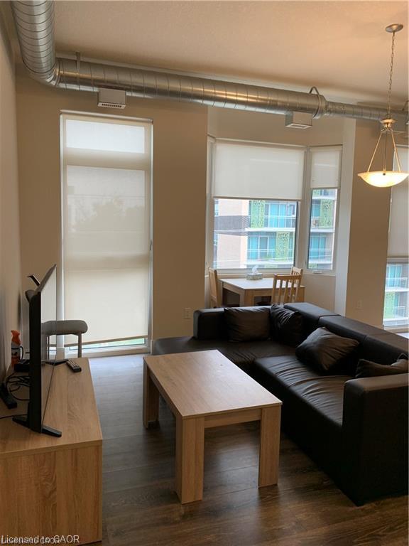 Exposed ductwork, wood-finish flooring, and multiple large windows with roller shades