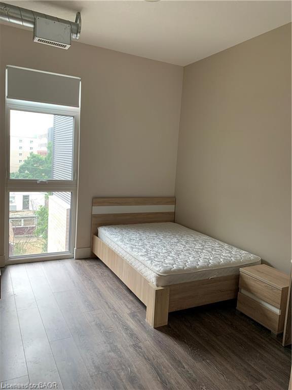Expansive window with roller shade, exposed ductwork, wood-finish flooring, neutral wall color, and white ceiling