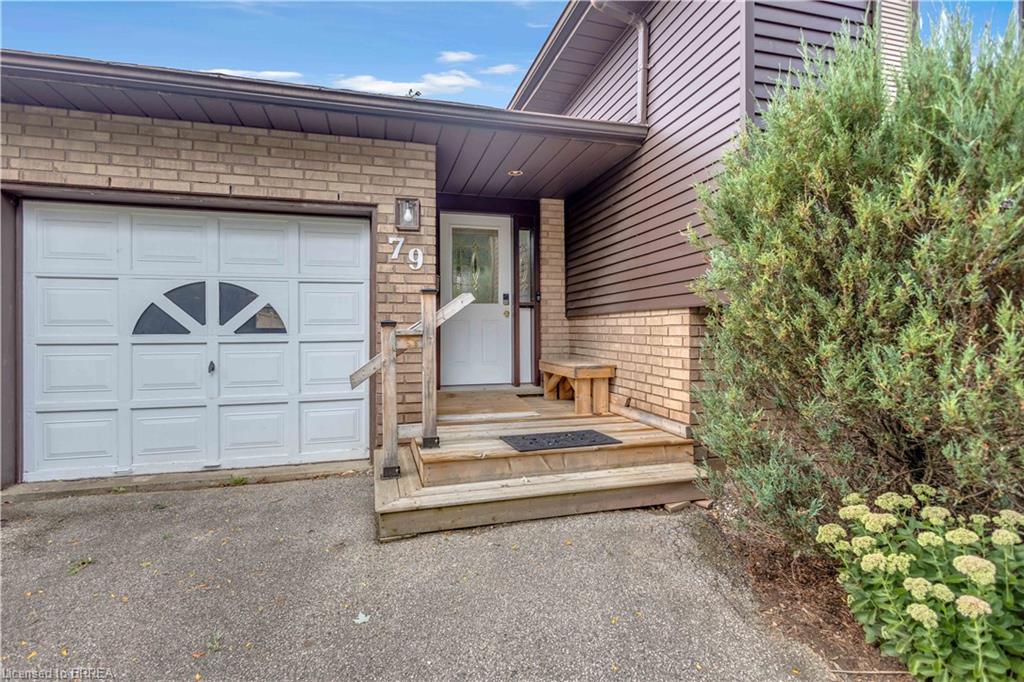 Brick and siding exterior with a dedicated entry, white garage door with decorative windows, and concrete driveway