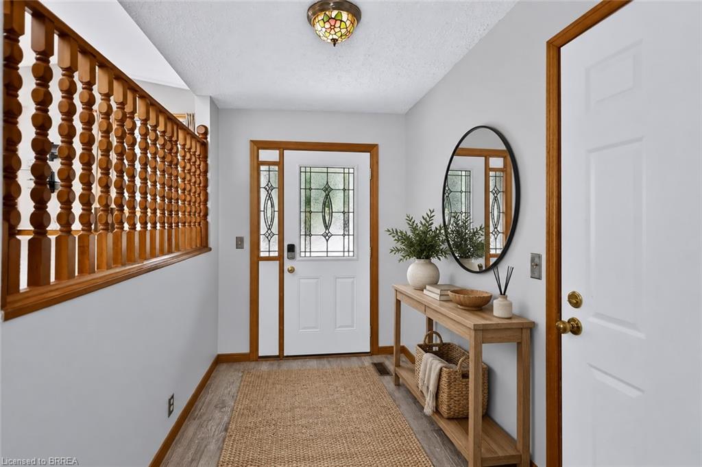 Entryway featuring a decorative glass paneled front door, wood-finish flooring, and a detailed wood banister