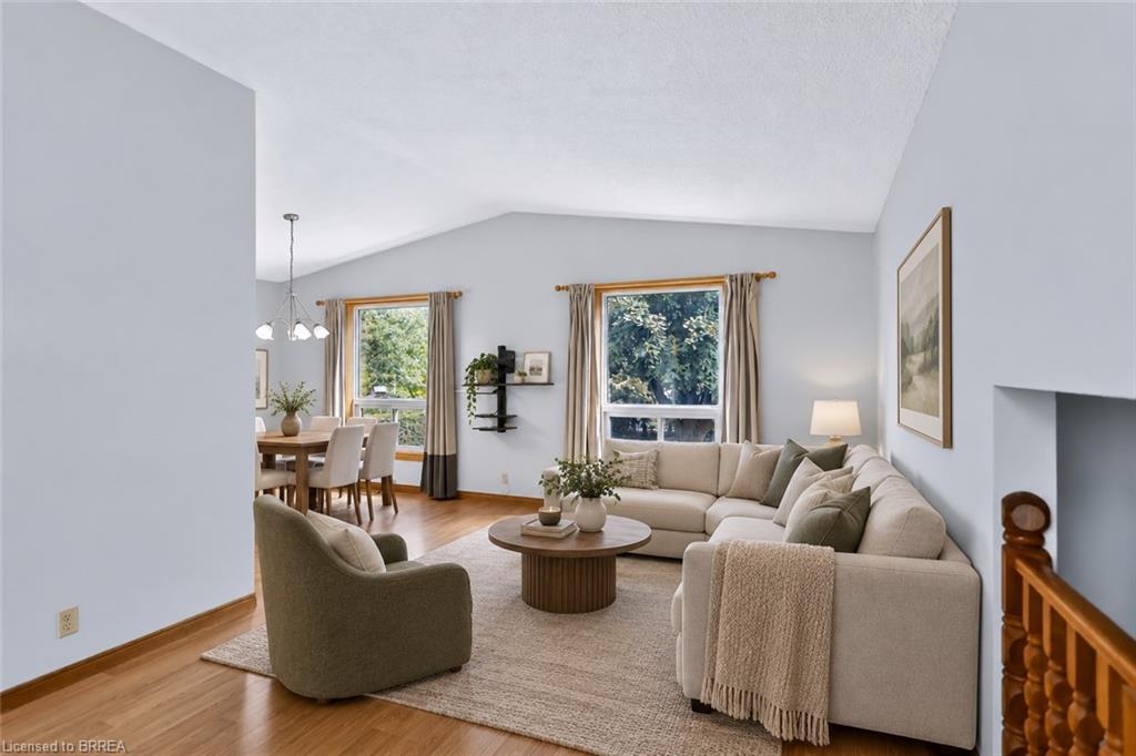 Vaulted ceiling, wood-finish flooring, large window, and dining area with pendant lighting