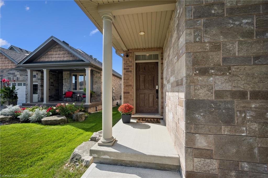 Stone and brick exterior with a covered entry, column, and a paneled front door