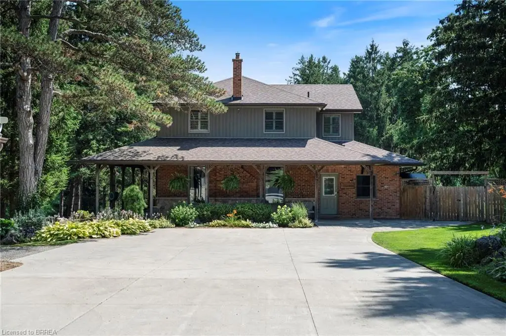 Traditional two-story residence featuring a brick and siding exterior, a full-width covered porch with wood columns, and a prominent brick chimney