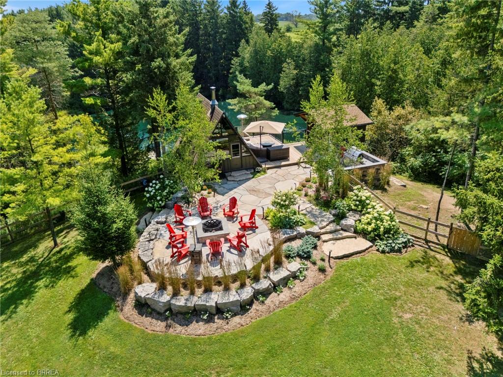 Expansive outdoor living area featuring a stone patio, built-in fire pit with seating, and a multi-level terraced landscape