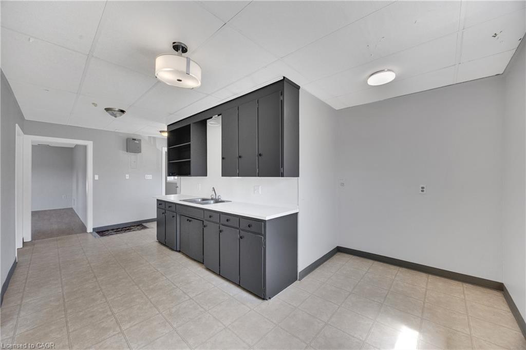 Modern kitchen and bath suite featuring a dark cabinetry island with white quartz countertop and integrated sink, complemented by matching wall-mounted cabinetry with mirrored medicine cabinet