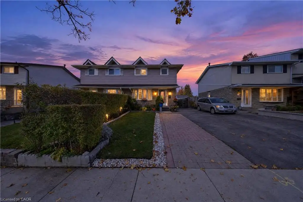 Multi-level exterior featuring a horizontal lap siding facade, three peaked gables, a paved stone driveway, and a front lawn with a stone-bordered garden bed