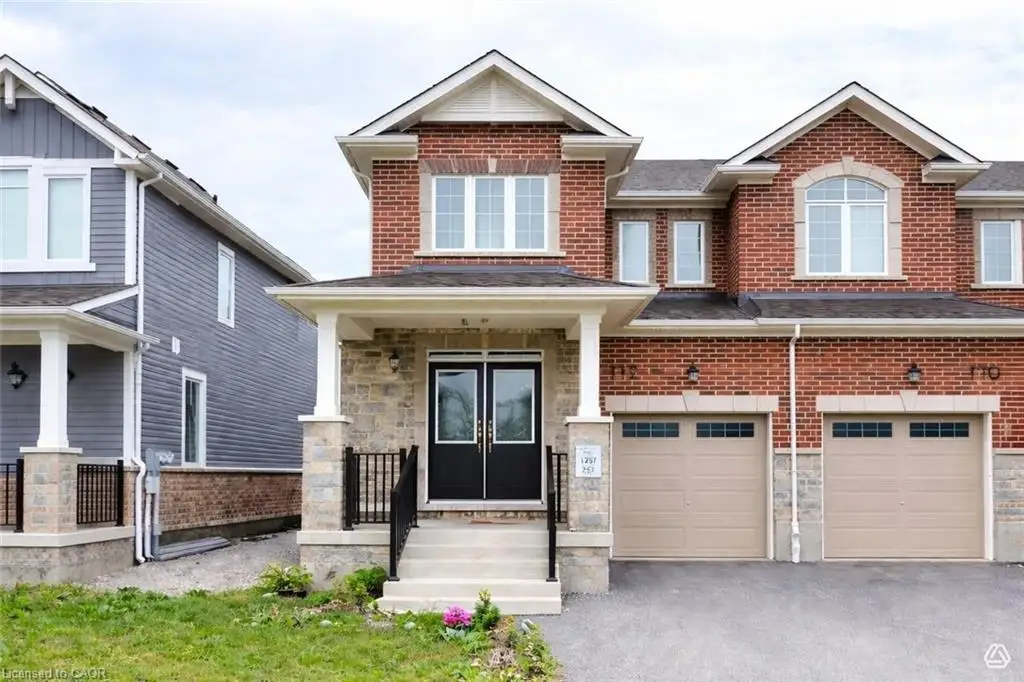 Brick and stone facade featuring a covered entry, black double doors, two vehicle garages, and multiple window styles