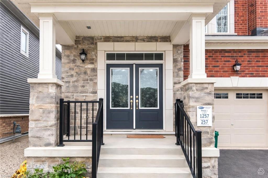 Covered entryway featuring a double door with glass panels, stone veneer accents, and white columns