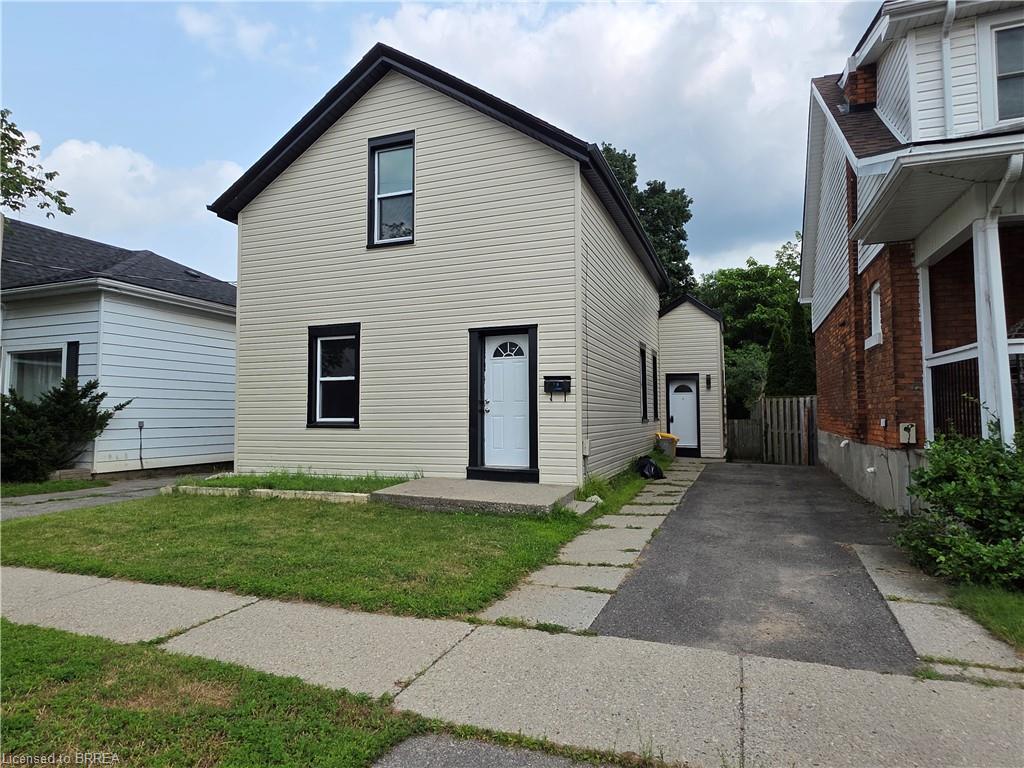 Two-story property featuring light-colored siding with contrasting dark trim and a dark roof