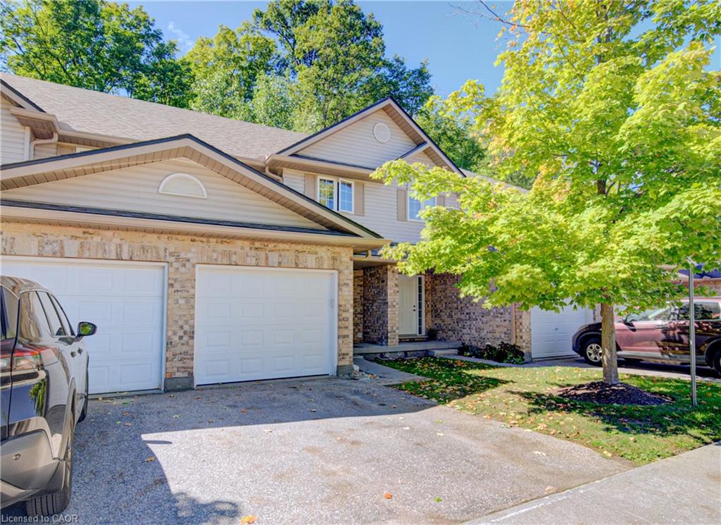 Brick and siding exterior with a shingled roof, two attached garages, and a paved driveway