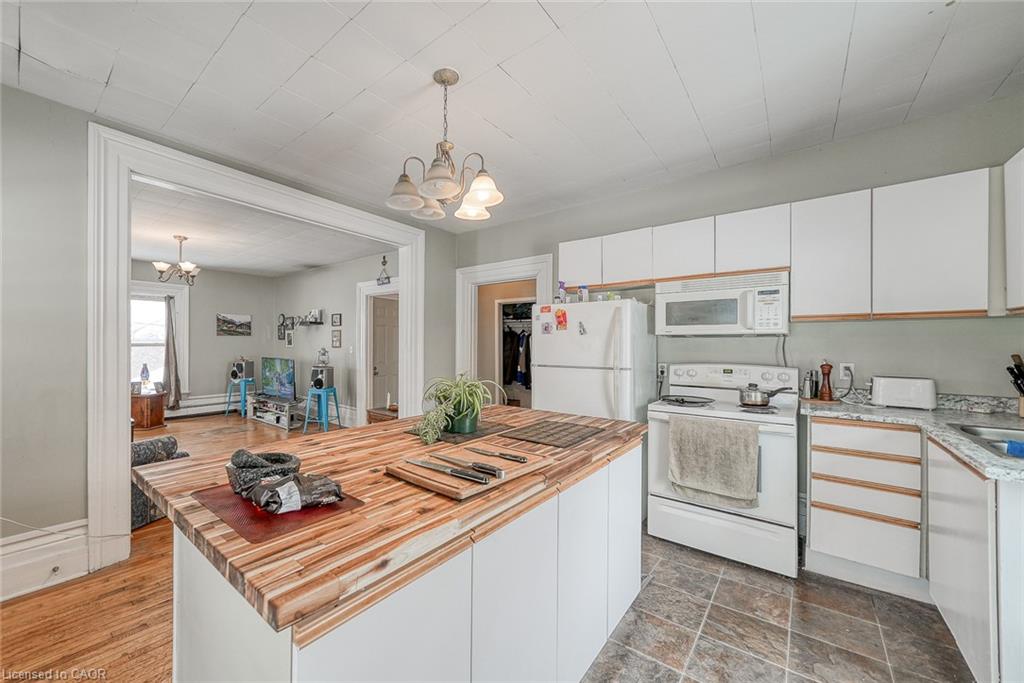 Kitchen featuring white cabinets, white appliances, a chandelier, and hanging light fixtures