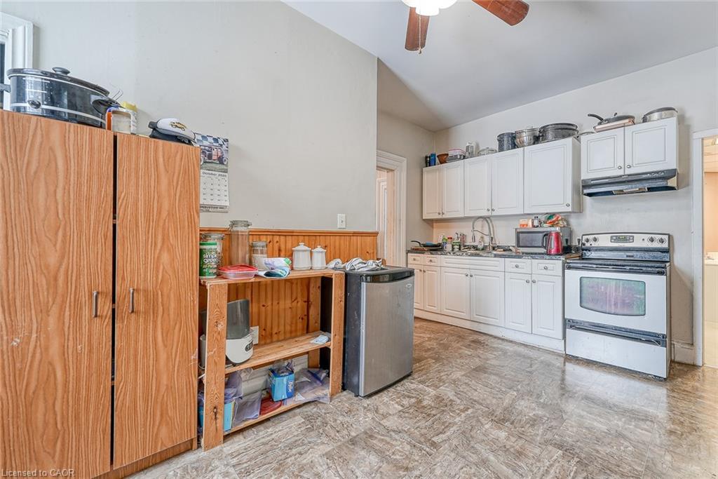 Kitchen featuring white electric stove, light flooring, under cabinet range hood, white cabinetry, and lofted ceiling