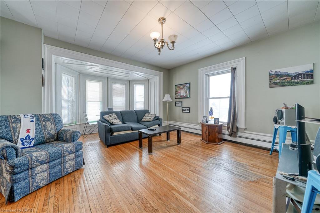 Living room with light wood finished floors, a chandelier, and baseboard heating