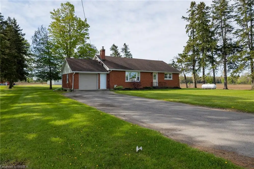 Single-story brick exterior with an attached garage, a paved driveway, and a shingled roof