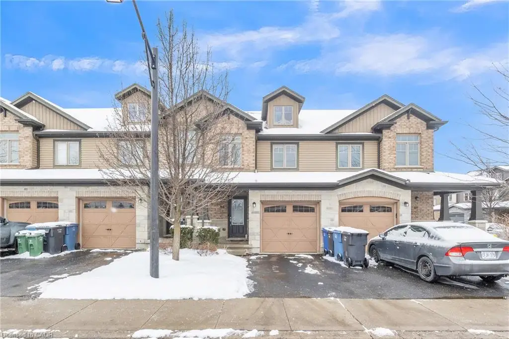 Brick and siding exterior with dormer windows, individual garage doors, and covered entryway