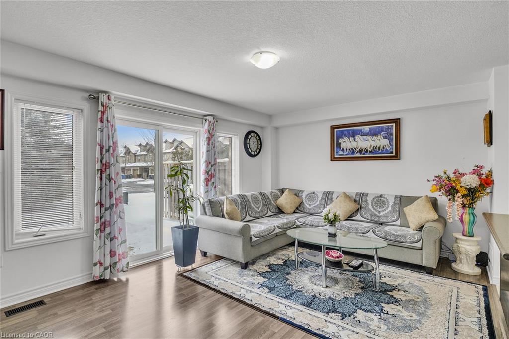 Wood-finish flooring, white walls, ceiling-mounted light fixture, sliding glass door, and a single-pane window