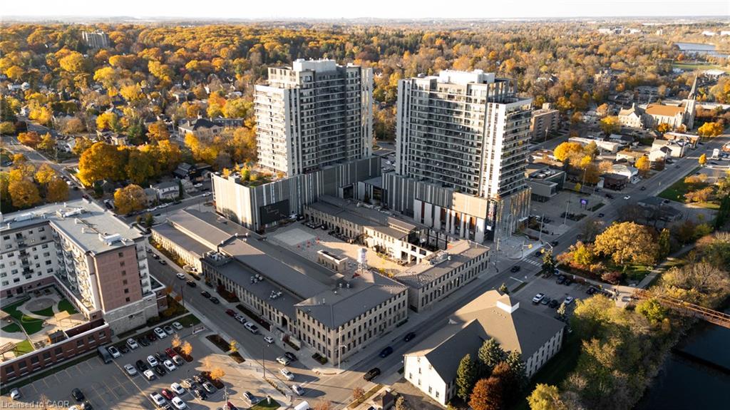 Modern high-rise residential buildings with multiple stories, surrounded by a mature tree canopy