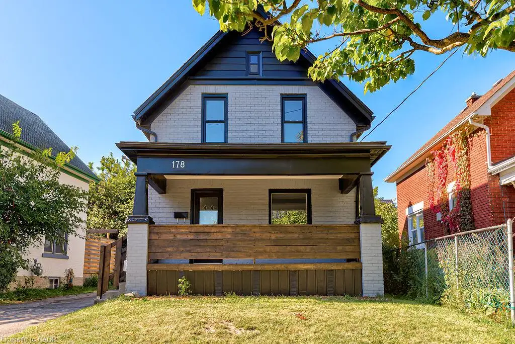 Brick exterior with dark trim accents, covered front porch, and wood-toned privacy screening