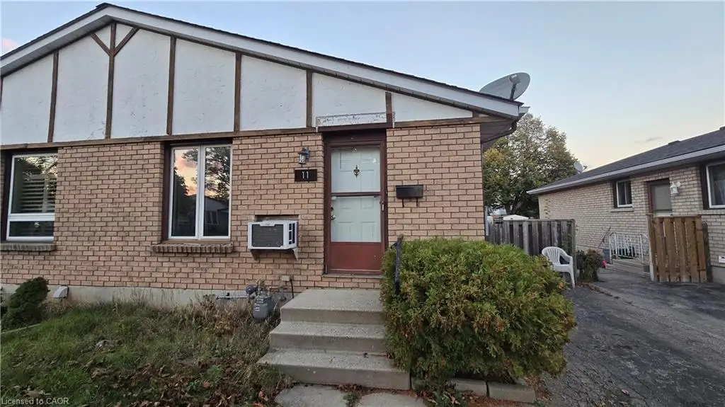 Exterior featuring brick masonry, timber-frame gable detailing, concrete entry steps, and vinyl-framed windows
