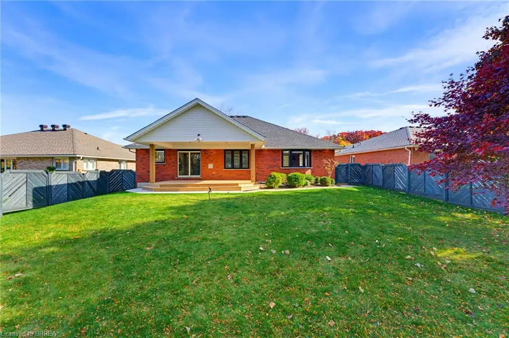 Rear exterior featuring red brick masonry, a covered porch with wooden support posts, a gabled roofline, and an enclosed backyard with wood fencing