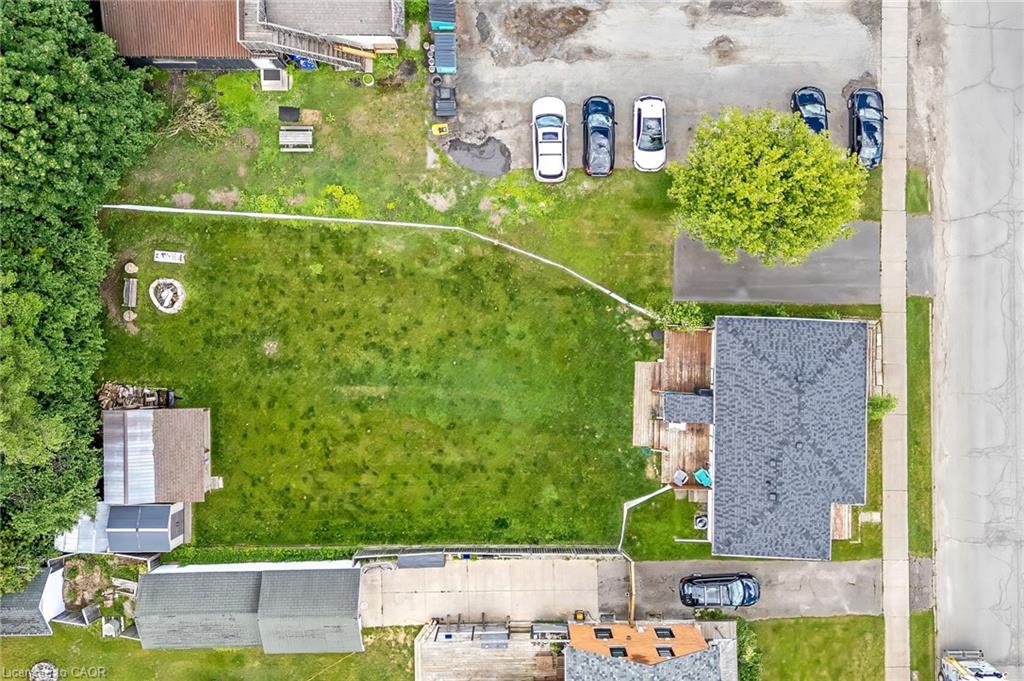 Expansive residential lot featuring a mature, manicured lawn with established trees, concrete hardscaping and patio areas, detached garage with shingled roof, and mature perimeter landscaping