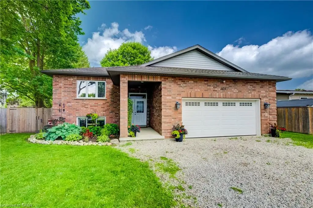 Brick exterior with a covered entry, white garage door, and a gravel driveway