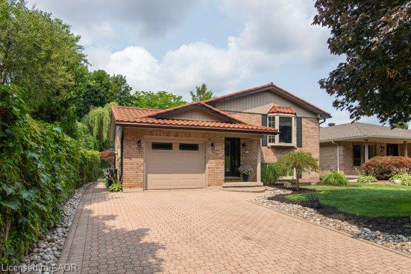 Brick exterior with a tiled roof, paver driveway, and an attached garage