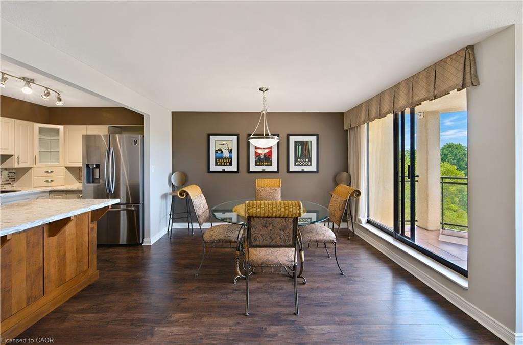 Open-concept living area featuring rich wood-finish flooring, a contemporary kitchen with cream cabinetry, and a spacious balcony with black metal railings