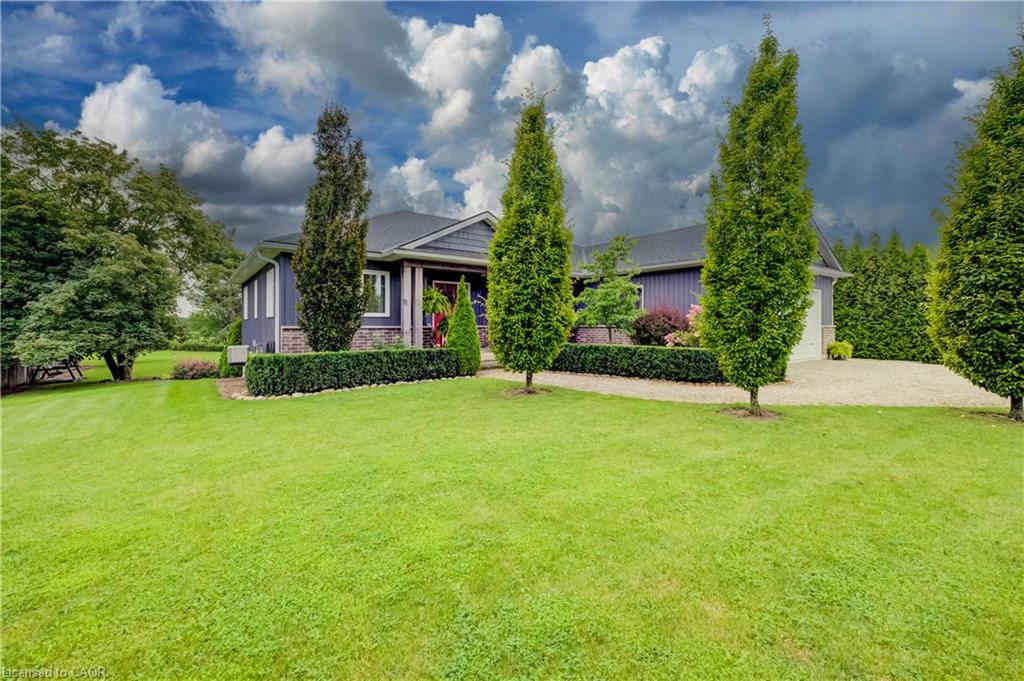 Expansive manicured lawn with lush green grounds and mature landscaping, anchored by tall columnar evergreens framing the property