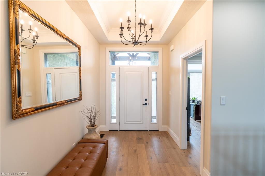Entryway featuring wood-finish flooring, a tray ceiling, and an ornate chandelier