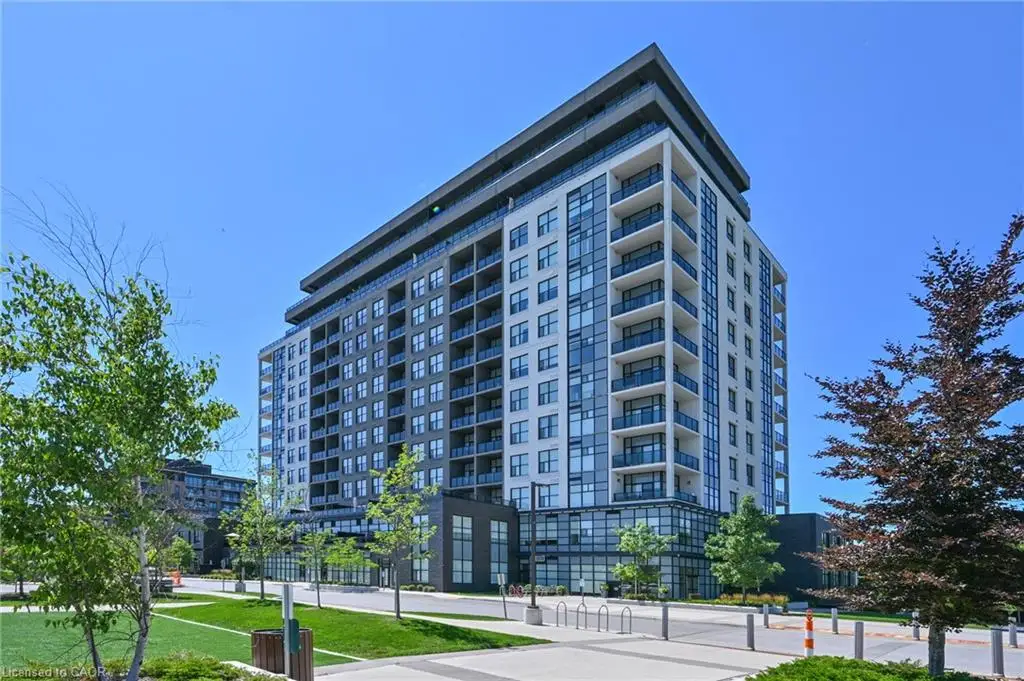 Contemporary high-rise building featuring a clean facade with white and gray paneling, multiple levels of balconies with glass railings, and expansive window lines