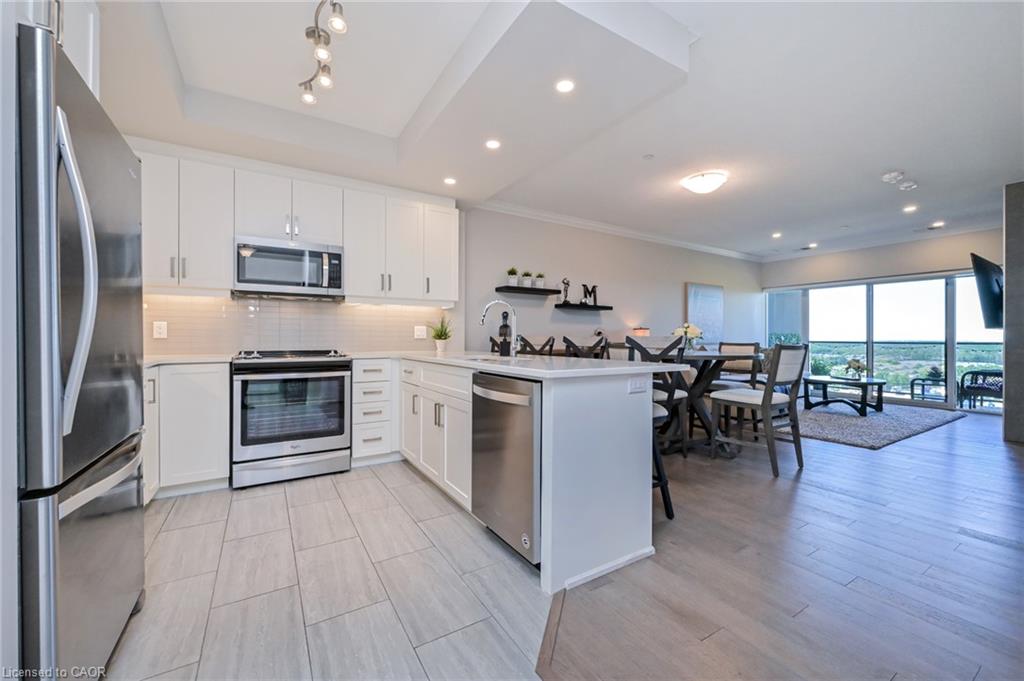 Modern kitchen featuring white cabinetry, stainless steel appliances, light-toned tile flooring, and an open-concept design