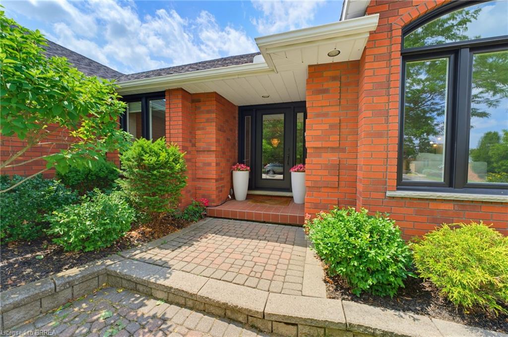 Brick facade exterior featuring a paver walkway, well-maintained landscaping, black-framed windows, and an arched transom window