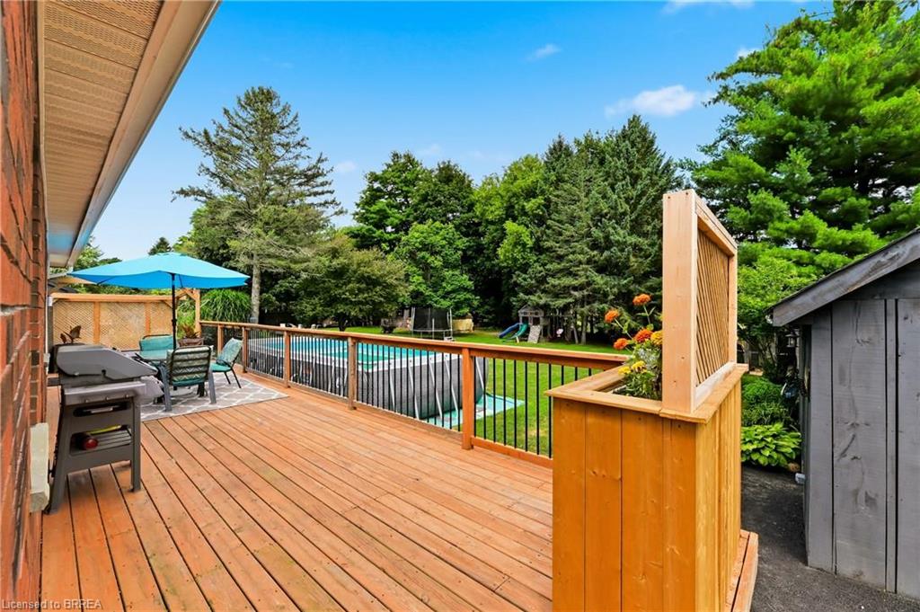 Expansive wood deck with black metal spindle railing, featuring a built-in planter box and direct access to an above-ground pool