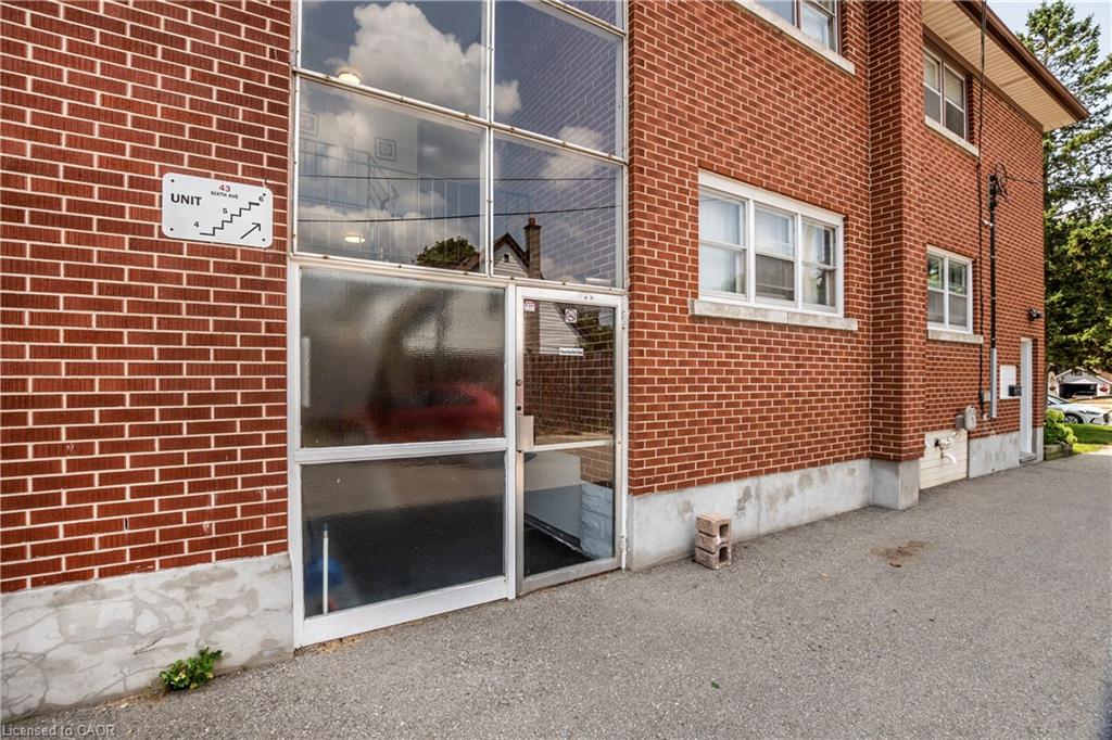 Red brick exterior with multiple windows, a glass-paneled entrance, and a concrete foundation