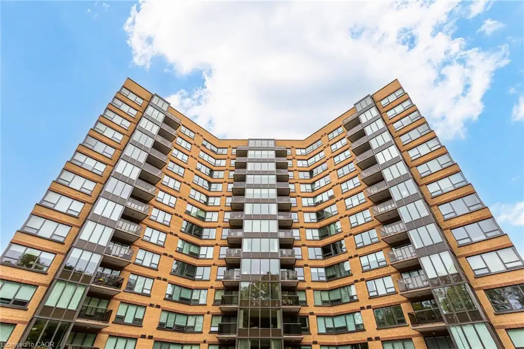 Mid-rise brick exterior featuring expansive glass windows, metal-framed balconies, and a stepped architectural facade