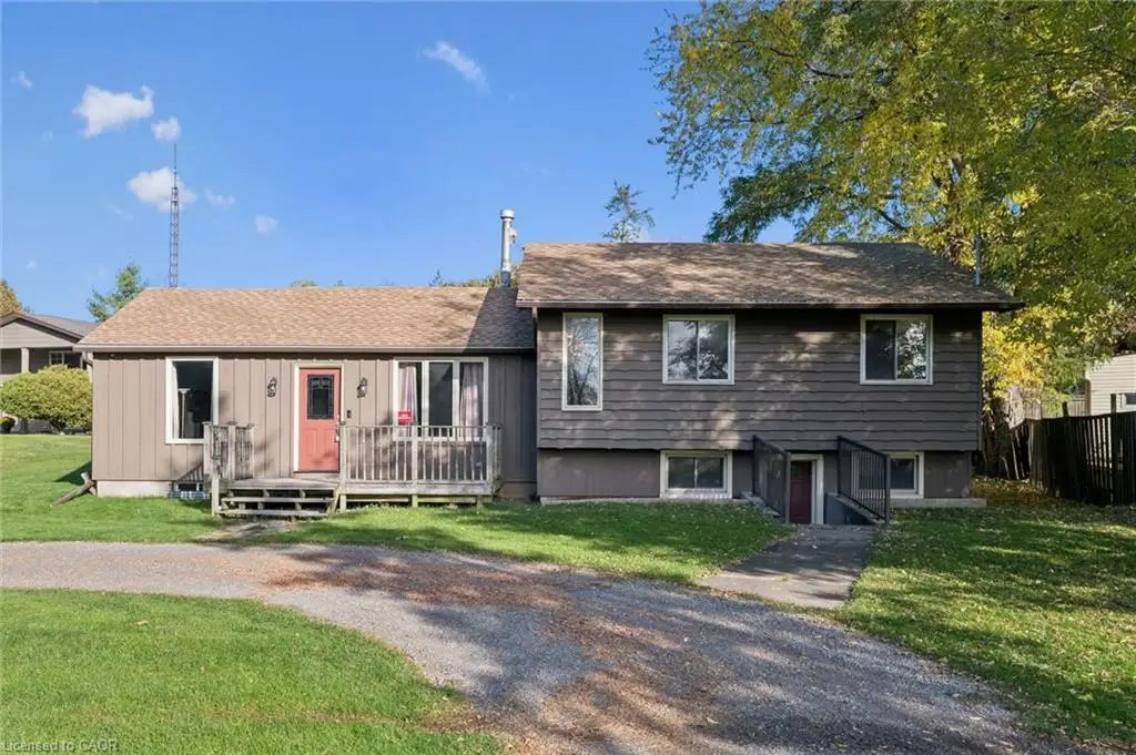 Split-level exterior featuring wood siding, asphalt shingle roofing, a front wood deck with railing, and a gravel driveway