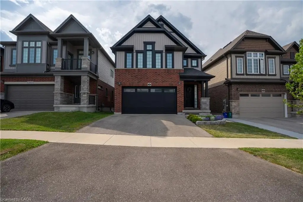 Brick and siding exterior with dark-framed windows, an attached garage, and a concrete driveway