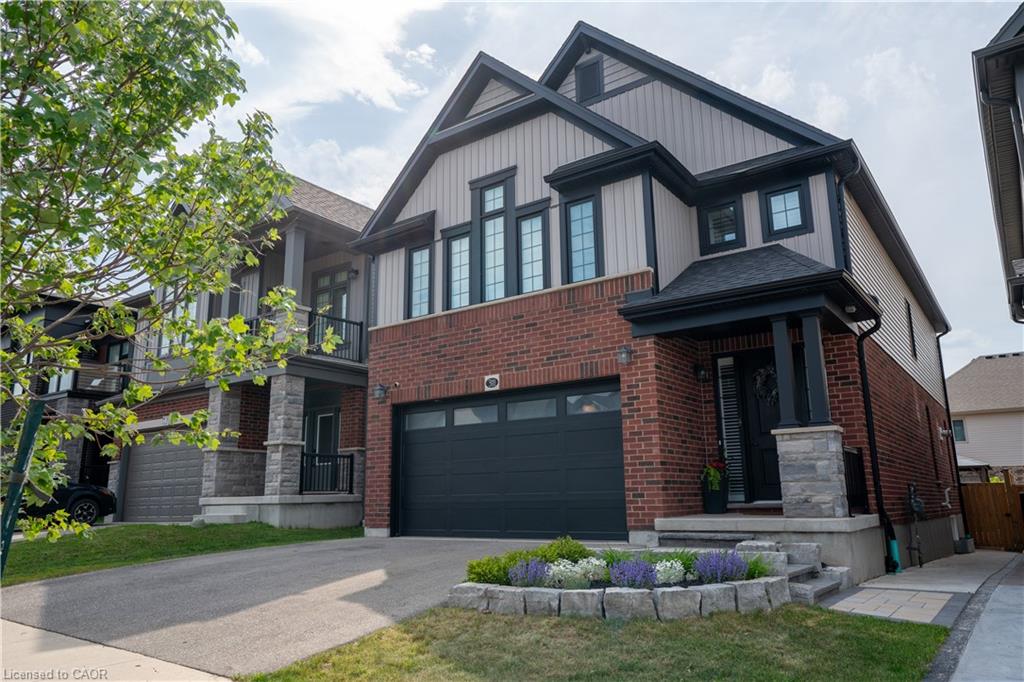 Brick and vertical siding exterior with a covered entry, attached garage, and stone-clad porch columns