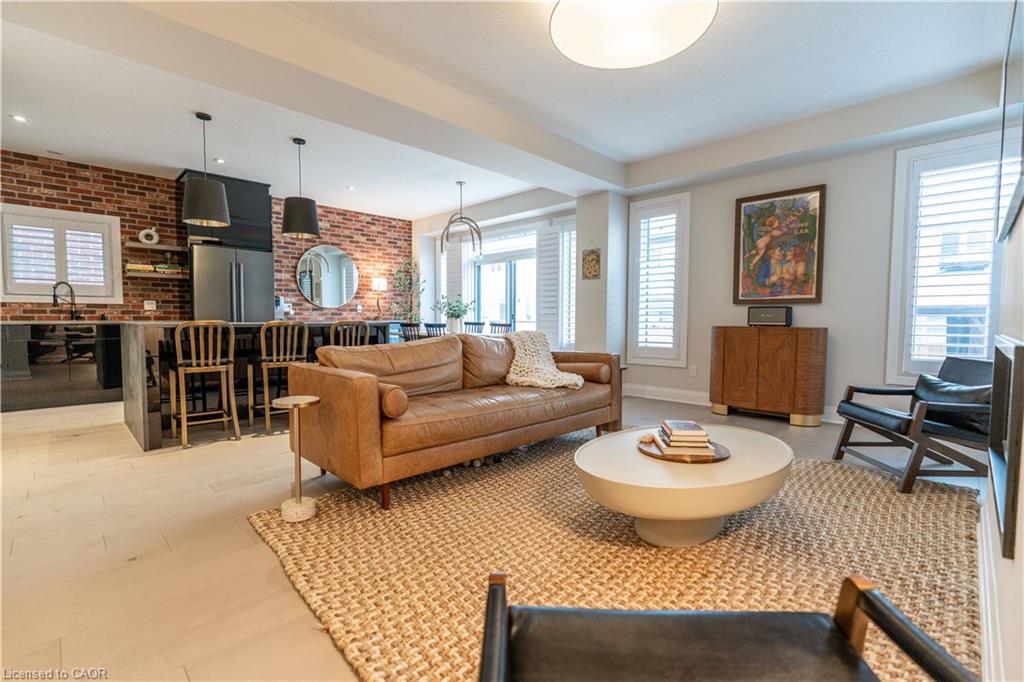 Open-concept living area featuring light wood-finish flooring, plantation shutters, and recessed lighting