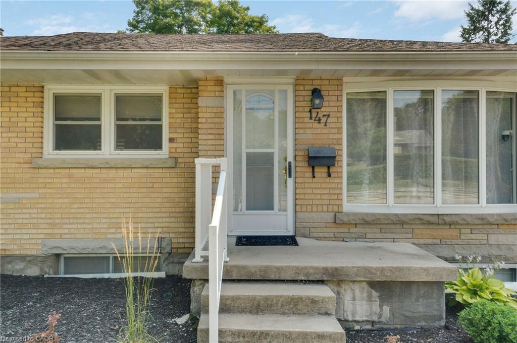 Brick and stone facade featuring a bay window, concrete entry steps, and a white storm door