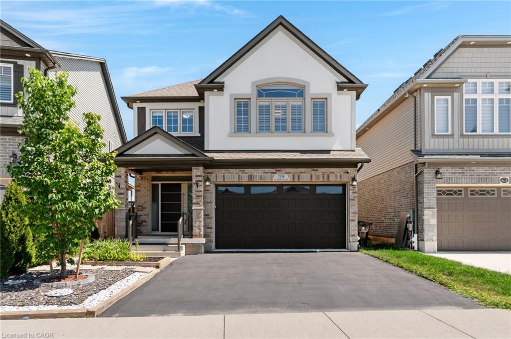 Striking two-story home featuring a crisp white and stone exterior with peaked roofline and arched transom windows