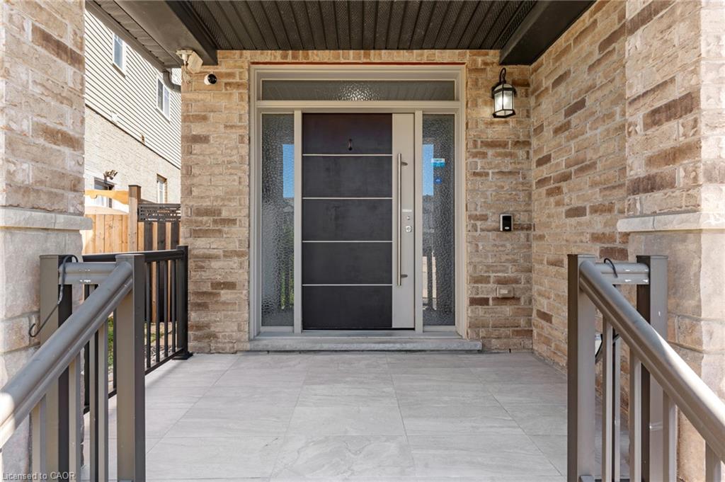Welcoming front entry featuring a modern black aluminum-frame door with horizontal glass panels, flanked by sidelights and framed by warm-toned brick masonry
